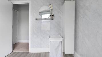 Een badkamer met een wit aanrecht, een ronde spiegel en een potplant.