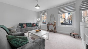 A modern living room with a grey sofa, a white coffee table, and a wooden console table with decorative items. - Shepherdess Place N1 🚇 Old Street 🚇 Angel (London)
