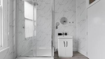 Een moderne badkamer met een douche met glazen wand, een wit wastafelmeubel met spiegel en wanden met een marmerlook.