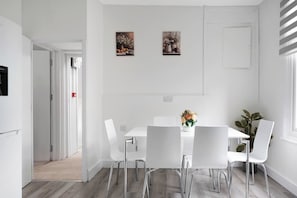A modern dining area with a white table and chairs, a vase of flowers, and two paintings on the wall. - Shepherdess Place N1, Old Street, Angel (London)