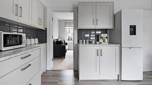 A modern kitchen with white cabinetry, a built-in microwave, and a refrigerator. - Shepherdess Place N1 🚇 Old Street 🚇 Angel (London)