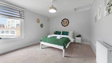 A bedroom with a bed, bedside table, and a radiator.