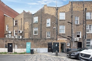 A row of brick buildings with multiple windows and doors, some with air conditioning units. - Shepherdess Place N1, Old Street, Angel (London)