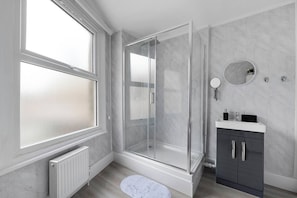 A modern bathroom with a glass shower enclosure, a white vanity, and a marble-tiled wall. - Shepherdess Place N1, Old Street, Angel (London)