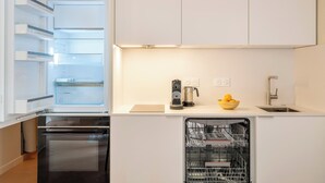 Eine moderne Küche mit Geschirrspüler, Kaffeemaschine und einer Obstschale auf der Arbeitsplatte.