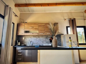 A modern kitchen with wooden cabinets, a stainless steel sink, and a vase with dried plants.