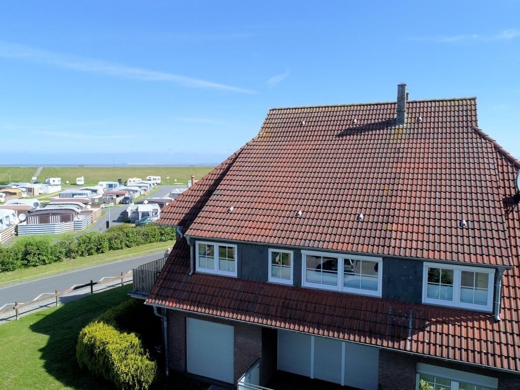 Ein Haus mit rotem Ziegeldach, einer Garage und einem Blick auf einen Wohnmobilstellplatz im Hintergrund.