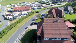 Zona residenziale con case, camper e una spiaggia sullo sfondo.