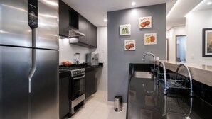 Una cocina moderna con electrodomésticos de acero inoxidable, horno empotrado y encimera negra.
