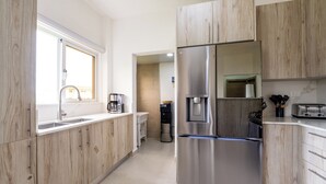 Eine moderne Küche mit Holzschränken, Edelstahlgeräten, einem Wasserspender und einem Toaster.