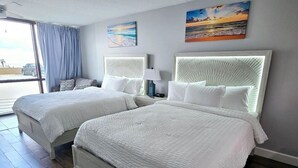 Una habitació d'hotel amb dos llits, una finestra gran amb cortines i obra d'art a les parets.