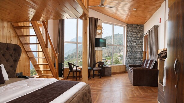 A bedroom with a large bed, a desk, a chair, and a TV. - Hotel Amadeus (Tehri)