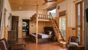 A wooden cabin interior with a bunk bed, a staircase, a dining area, and a bathroom. - Hotel Amadeus (Tehri)
