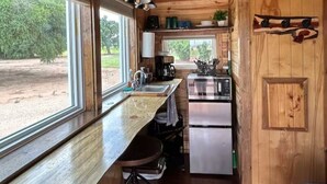 A compact kitchen with a wooden countertop, a sink, a coffee maker, and a refrigerator. - Bob White Tiny Cabin (Quitaque)