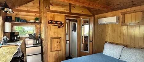 Une cabane rustique équipée d’une kitchenette, d’un lit et d’une petite salle de bain.
