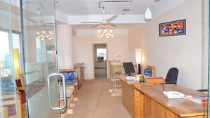 A modern office with glass partitions, wooden desks, and a ceiling fan. - Hotel Titas View Brahmanbaria (Brahmanbaria Sadar)