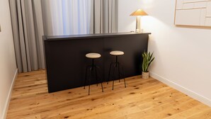 A modern bar area with a black countertop, two stools, a table lamp, and a potted plant. - Eternal Suites Rome (Rome)