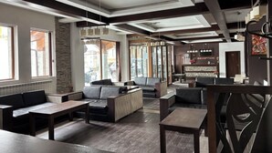 A modern hotel lobby with seating areas, a reception desk, and large windows. - ✨ Elegant Mountain Apartment with Fireplace, Balcony Views, SKI In&Out ⛷ (Bansko)