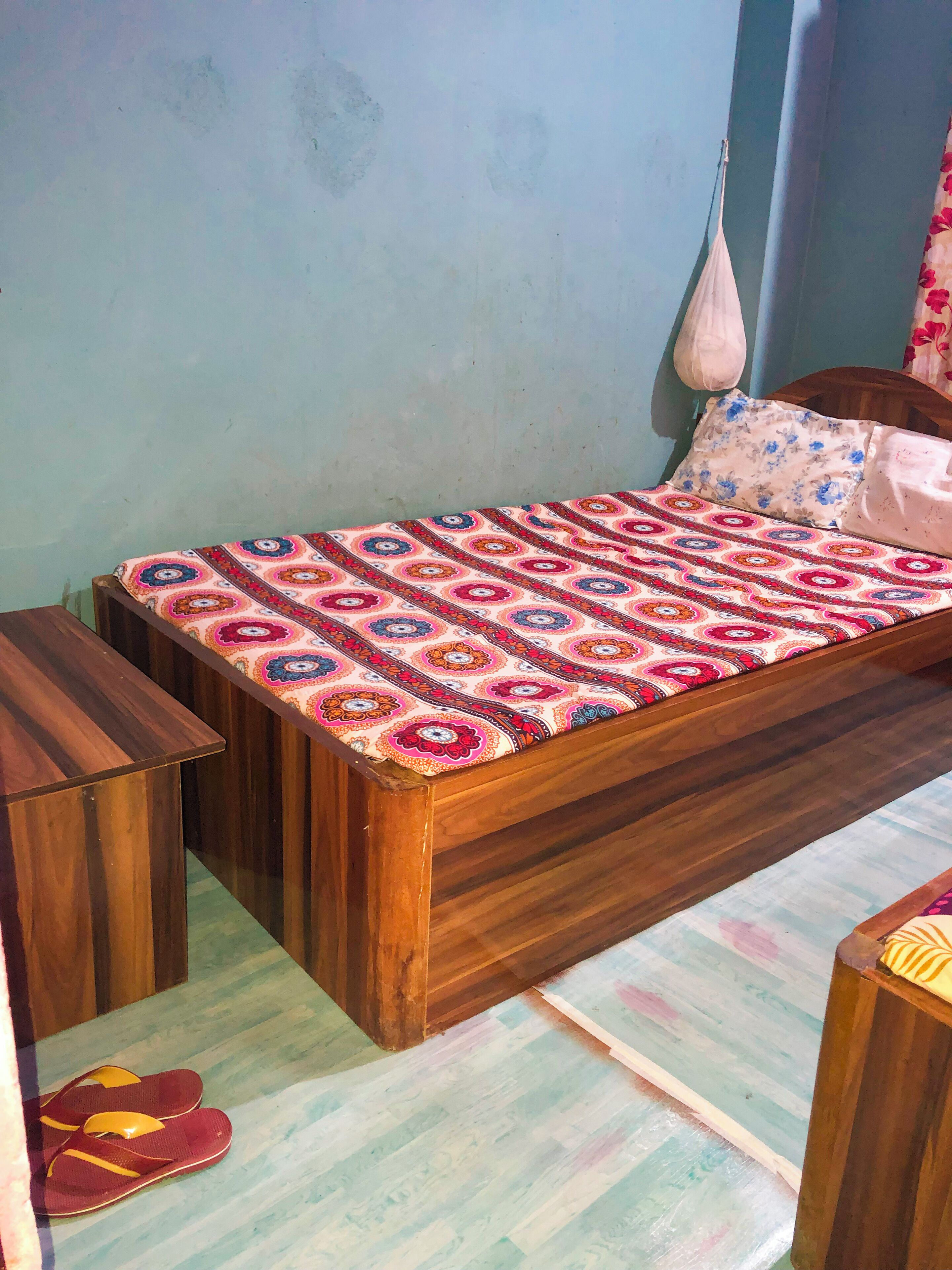 A single bed with a patterned bedspread, wooden headboard, and matching nightstands.