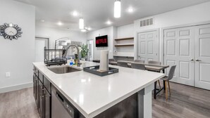 Een moderne keuken met een centraal eiland, inbouwapparatuur en hanglampen.