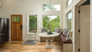 A modern kitchen with a built-in refrigerator, a wooden door, and a round dining table with a vase and pillows. - the Birdhouse of Boone, Luxe + Long Views + Charming Tiny Home (Boone)