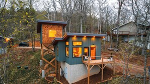 A modern cabin with a wooden deck, large windows, and a stone fireplace. - the Birdhouse of Boone, Luxe + Long Views + Charming Tiny Home (Boone)