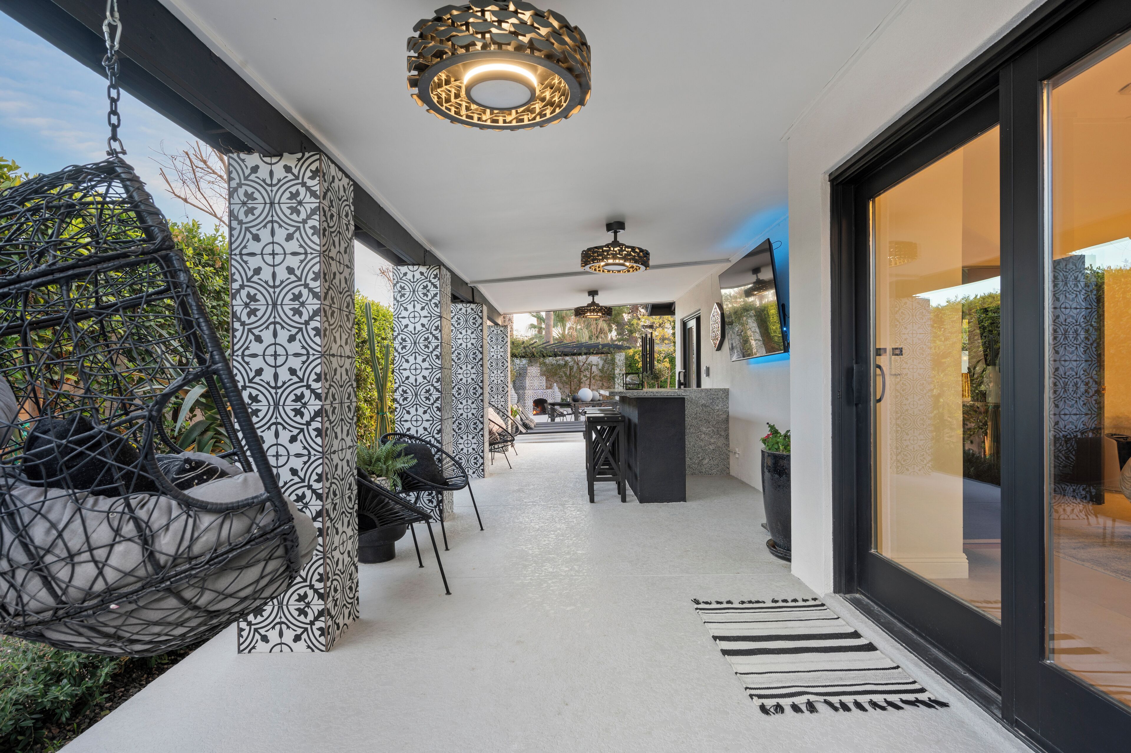 Een modern interieur met hangstoelen, gepatteerde zuilen en een centrale zithoek met een bar.