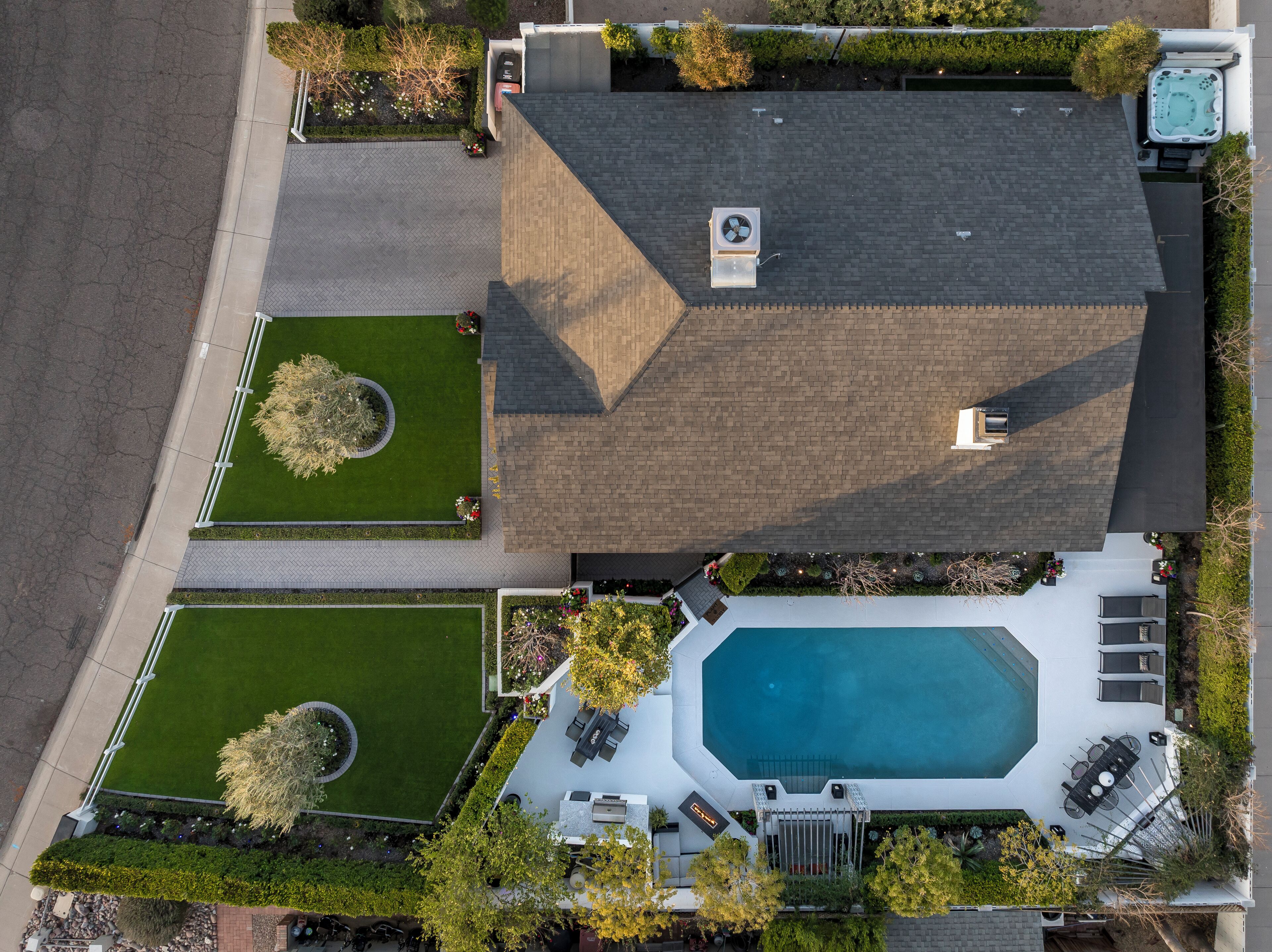 A residential property with a swimming pool, two well-maintained lawns, and a covered patio area.