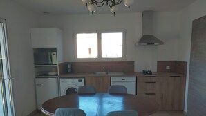 Cuina moderna amb taula i caires, rentadora, rentavaixelles i finestra amb llum natural.