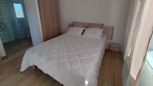 Un dormitori amb un llit gran, un panell de capçal de fusta i una petita taula de nit.