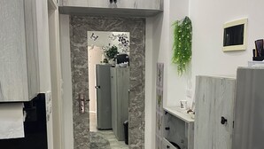 Een smalle keuken met grijze kastjes, een marmeren spatwand en een klein vloerkleed.