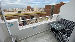Een balkon met uitzicht op de stadsgezicht, een tafel en een stoel.