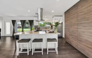 A modern kitchen with a central island, white cabinetry, and a view of the outdoors.