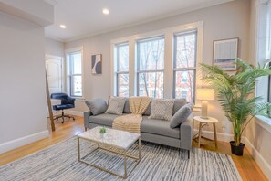 En moderne stue med en grå sofa, et sofabord og en potteplante.