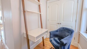 Een kamer met een wit bureau, een blauwe stoel en een witte deur.