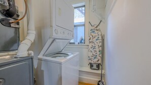 Een kleine wasruimte met een voorlader wasmachine, een droger en een uithangroede.