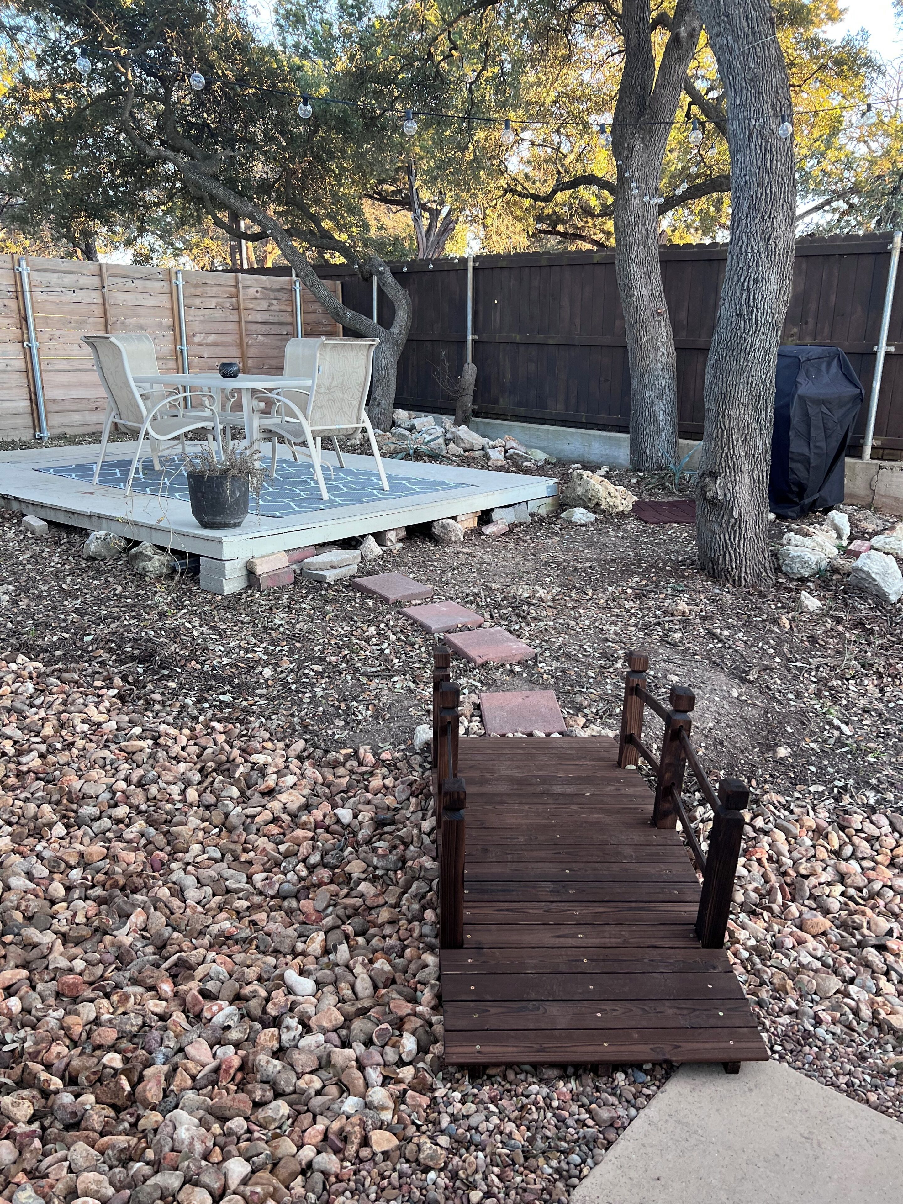 A wooden deck leading to a pool area with chairs and a table.