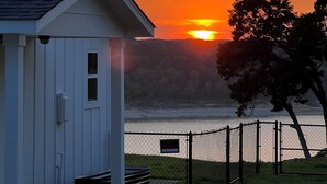 A white building with a sloped roof, a small porch, and a chain-link fence in front. - LAKE THERAPY- Cozy Lakeside with Beautiful Sunsets! (Temple)