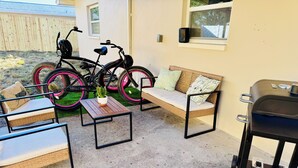 Eine Terrasse mit Gartenmöbeln, einem Fahrrad und einem Grill.