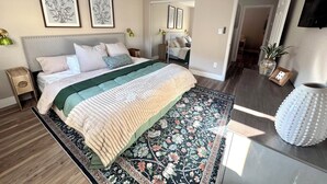 Ein Schlafzimmer mit einem Bett, Nachttischen, einem großen Teppich und gerahmten Bildern an der Wand.