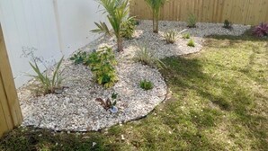 Ein Gartenbereich mit verschiedenen Pflanzen und einem Holzzaun.