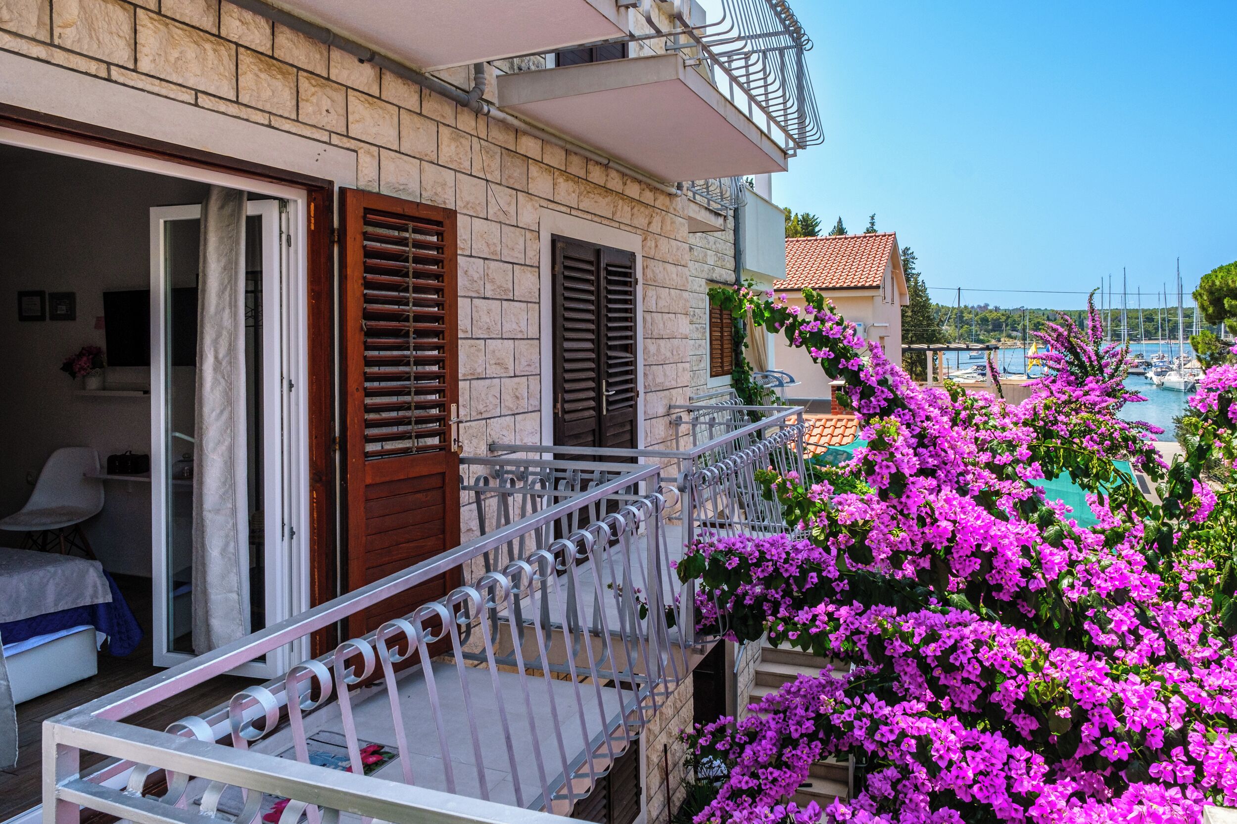 A hotel room with a balcony overlooking a marina and a pool.