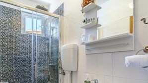 Ein modernes Badezimmer mit einer Duschkabine aus Glas, einem weißen Waschbecken und einer Toilette.