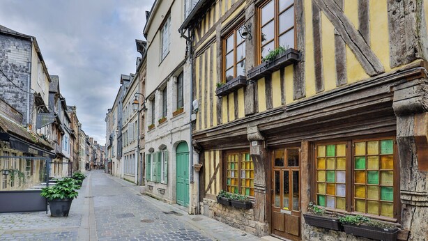 A narrow cobblestone street lined with historic buildings, some with visible shop fronts and windows. - Maison 1505 | Authentic 16th-century shipowner’s house in the city center (Honfleur)