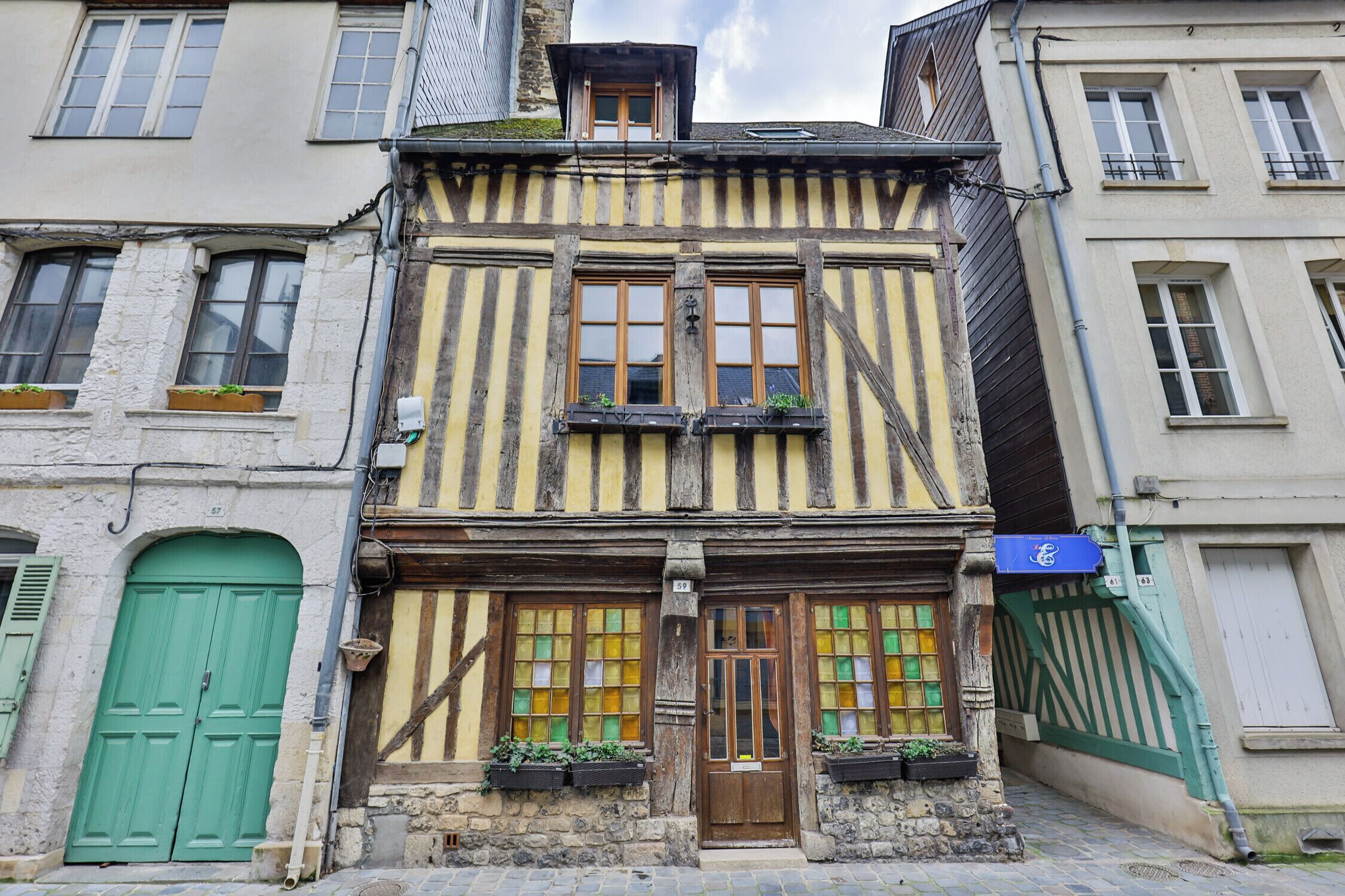 Un edificio tradicional con entramado de madera, una puerta verde, varias ventanas y un pequeño balcón.