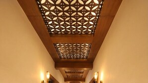 A long, narrow hallway with wooden paneling and a patterned ceiling. - Hanuman Heritage (Chikkamagaluru)