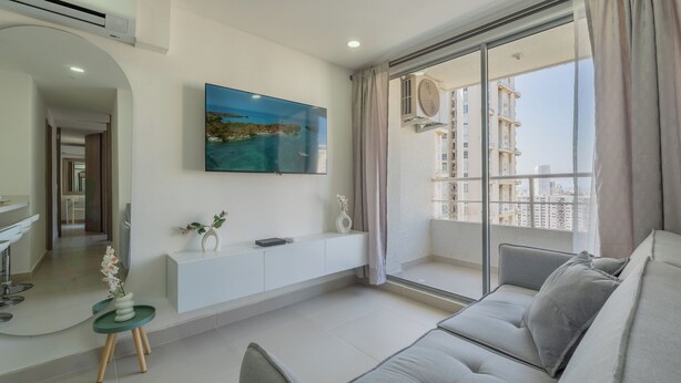 Uma sala de estar moderna com uma janela grande, um sofá, uma mesinha de centro com uma planta e uma TV na parede.