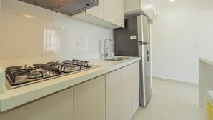 Cozinha moderna com fogão a gás, geladeira de aço inoxidável e armários brancos.