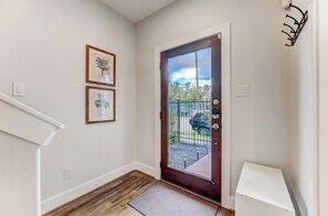 A hallway with a wooden floor, a white door with a glass panel, and a small white table. - Modern Midtown Getaway with City Views (Houston)