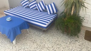 A bed with blue and white striped bedding, a small table with a blue tablecloth, and a potted plant beside the bed.